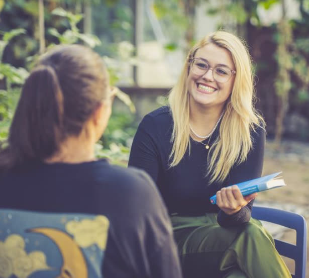 Caroline Uhl im Gespräch mit einer Klientin, ein Buch in der Hand